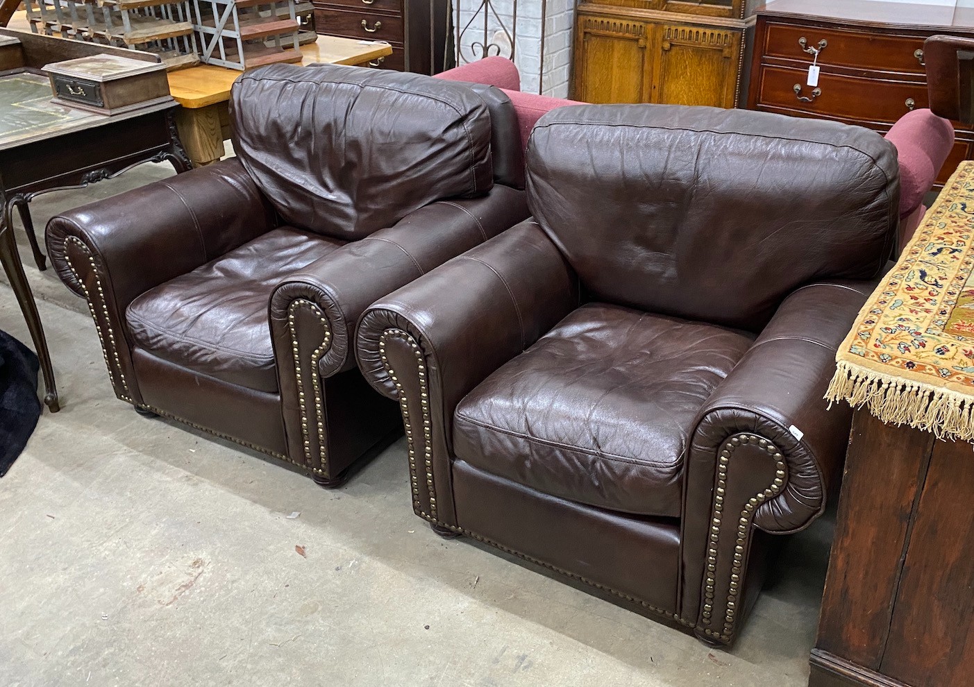 A pair of contemporary studded brown leather armchairs, width 98cm, depth 84cm, height 80cm